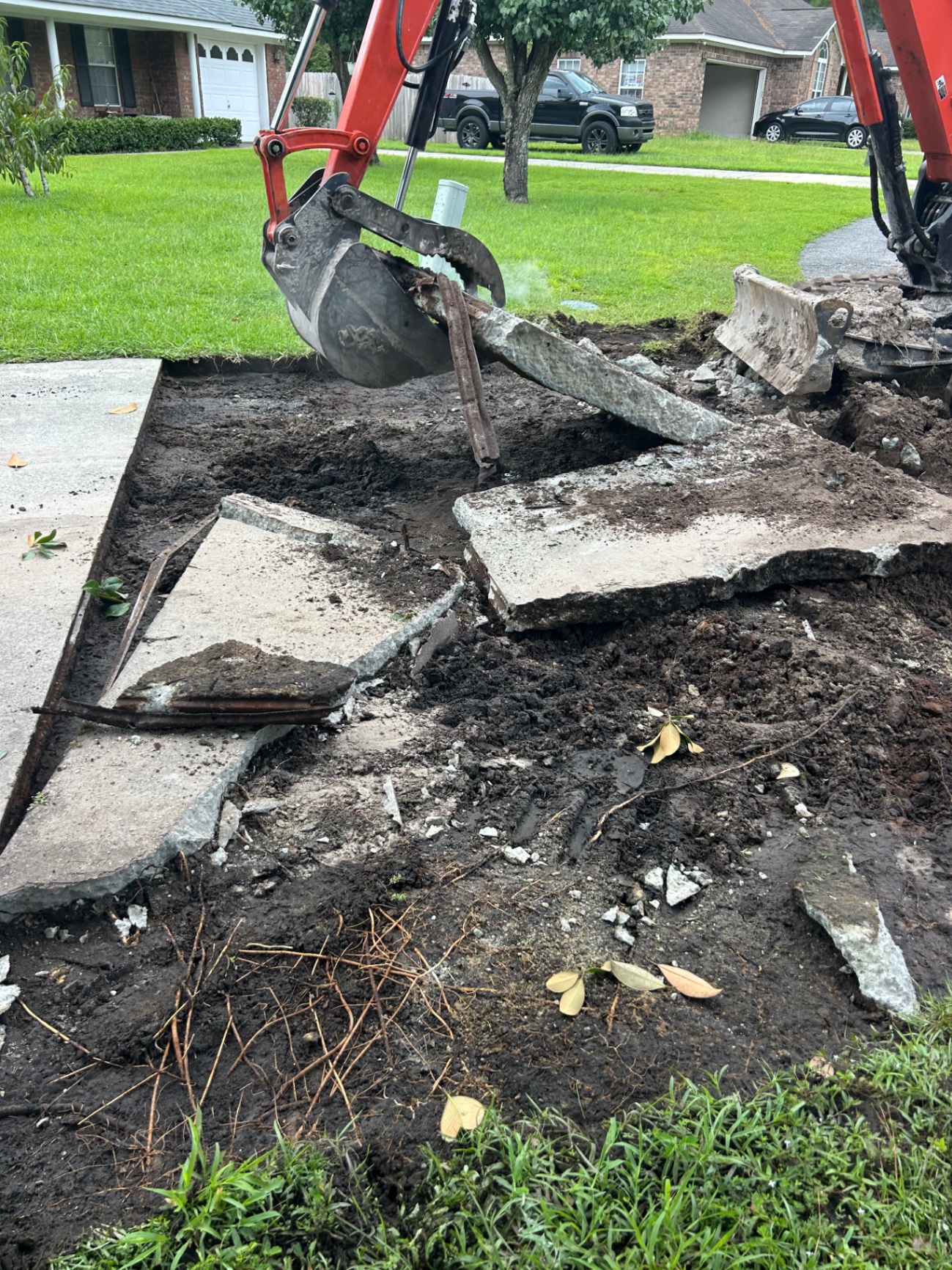 Excavator tearing out an old concrete driveway